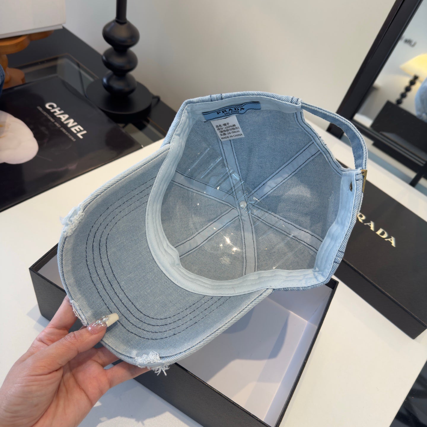 A light blue distressed denim baseball cap with a triangular embroidered patch on the front.