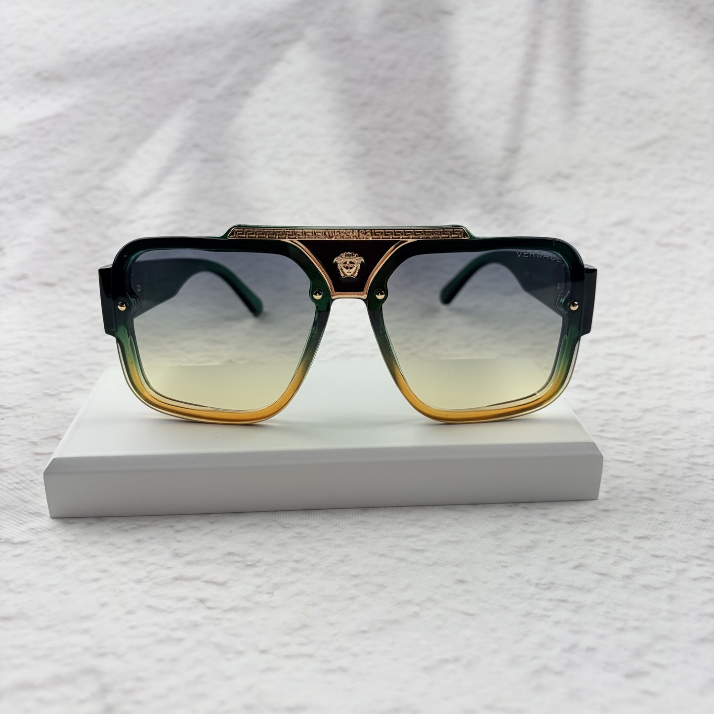 Oversized geometric sunglasses with green-to-yellow gradient lenses and gold metallic frame details.