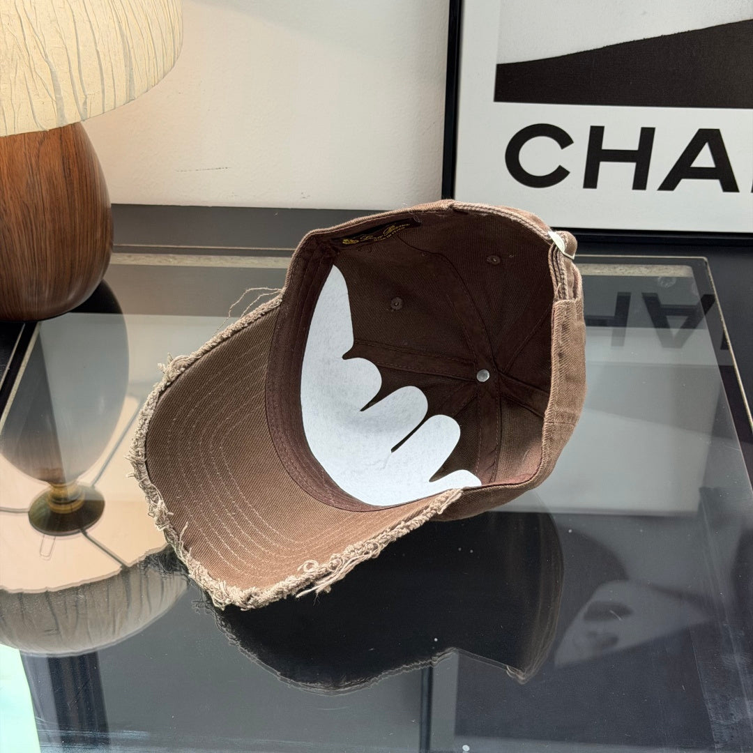 Distressed brown cotton baseball cap with frayed brim and minimalist metal circular side detail.