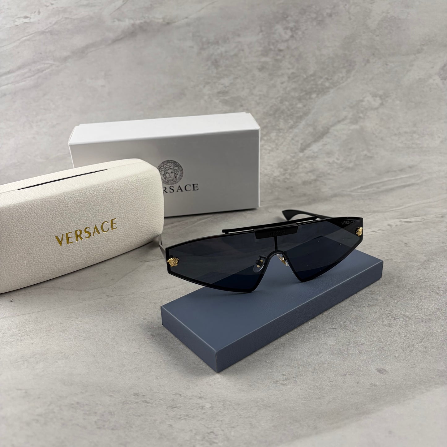 Modern shield sunglasses with a sleek black frame and dark tinted lenses on a grey background.