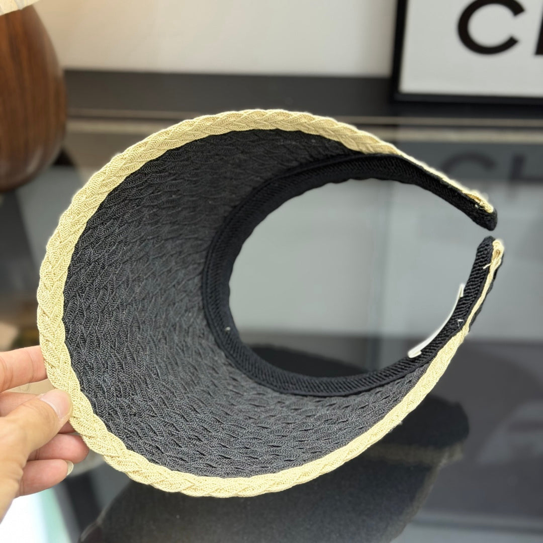 Close-up of a stylish woven straw sun visor with contrast border and white emblem detail.