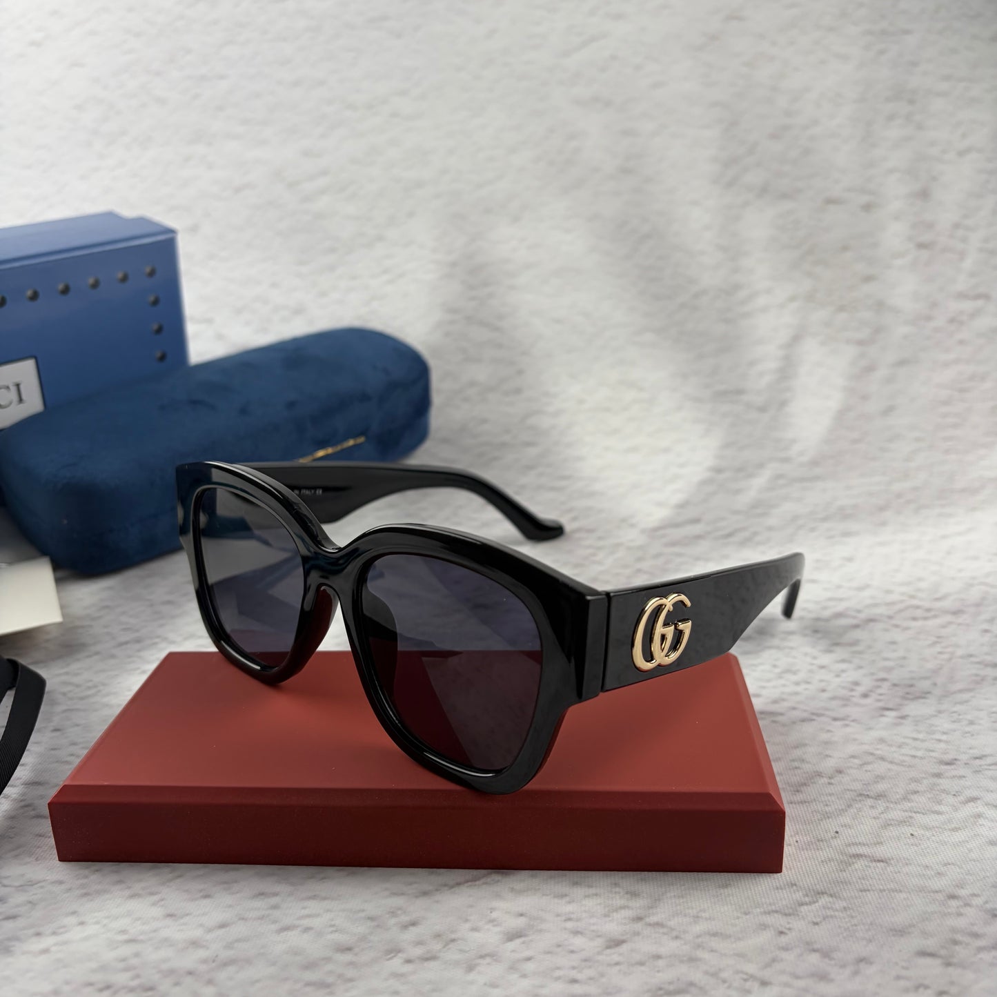 Oversized black frame sunglasses with dark gradient lenses and gold-tone logo detailing on temples.