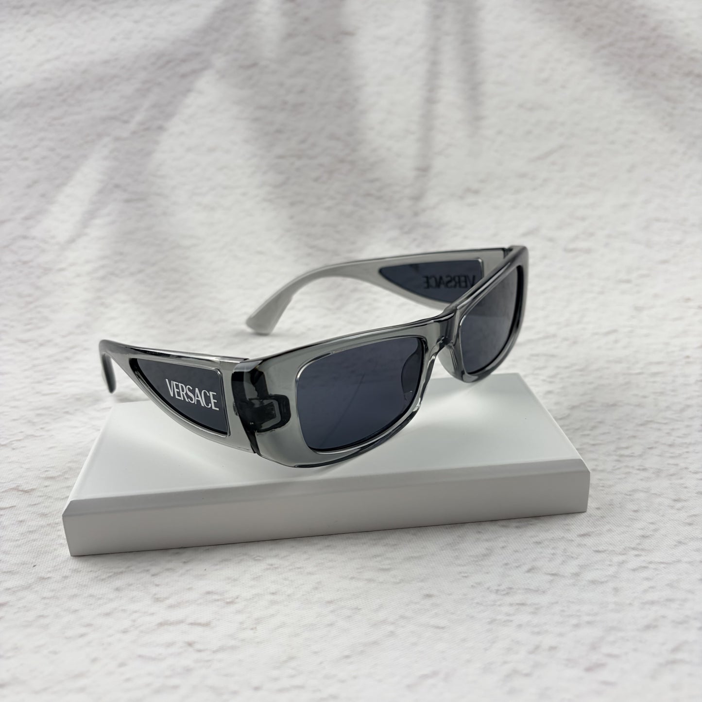 Modern rectangular sunglasses in translucent gray with dark tinted lenses, includes protective case.