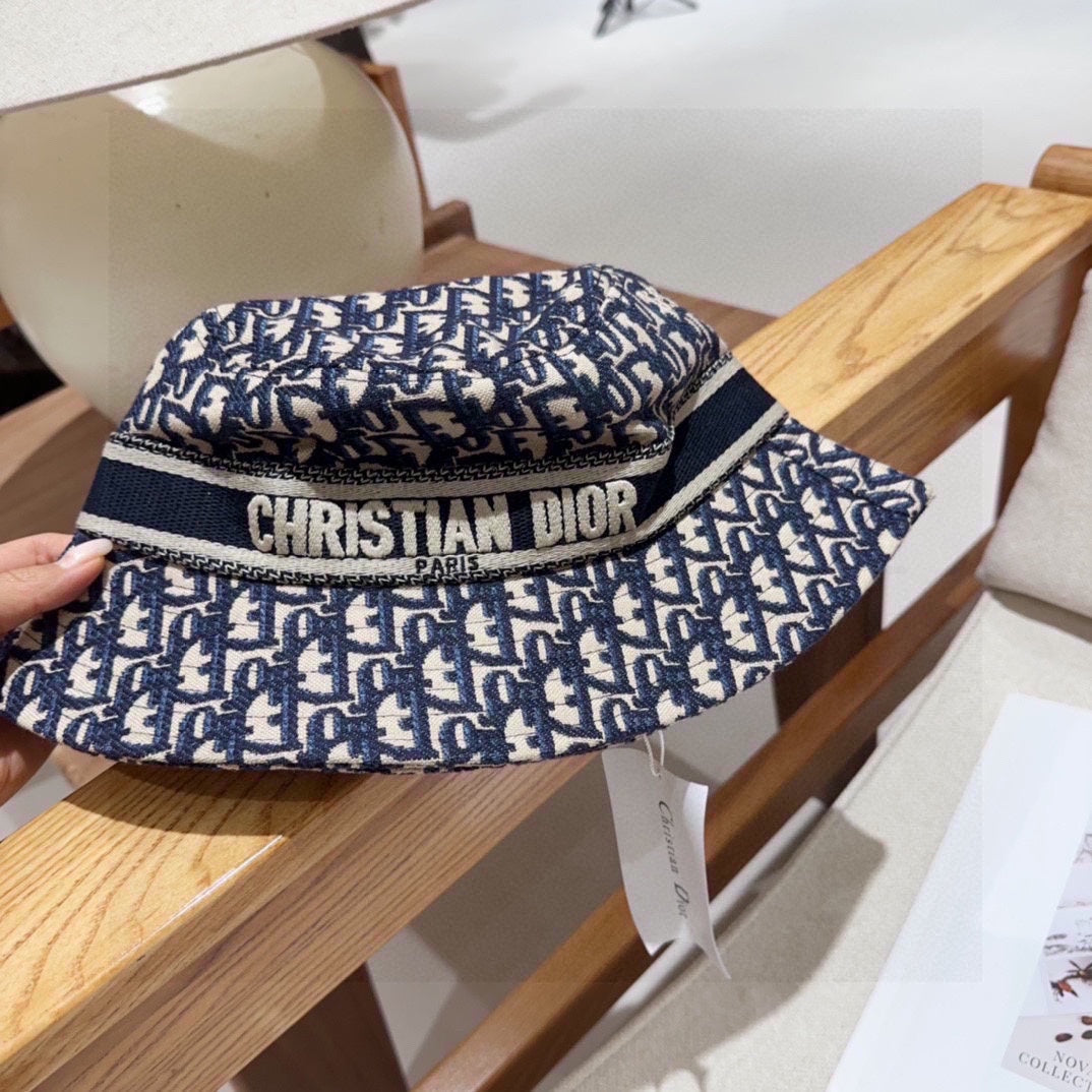 Close-up of a blue and beige monogram patterned cotton bucket hat with a wide brim and fabric band.