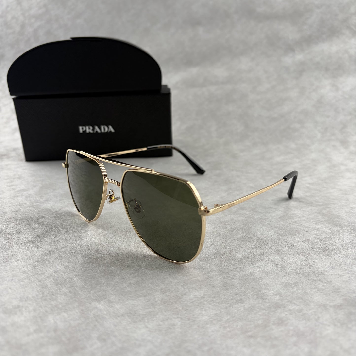 Classic gold-tone metal aviator sunglasses with tinted lenses, resting next to a protective case.