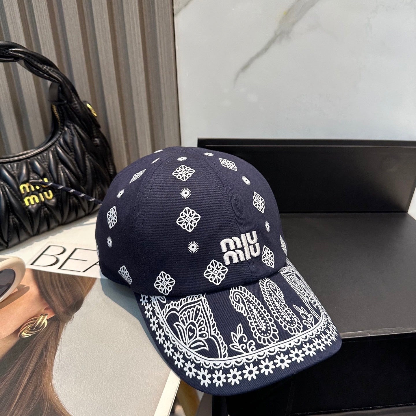 Navy blue baseball cap with white embroidered paisley patterns and an adjustable back strap.