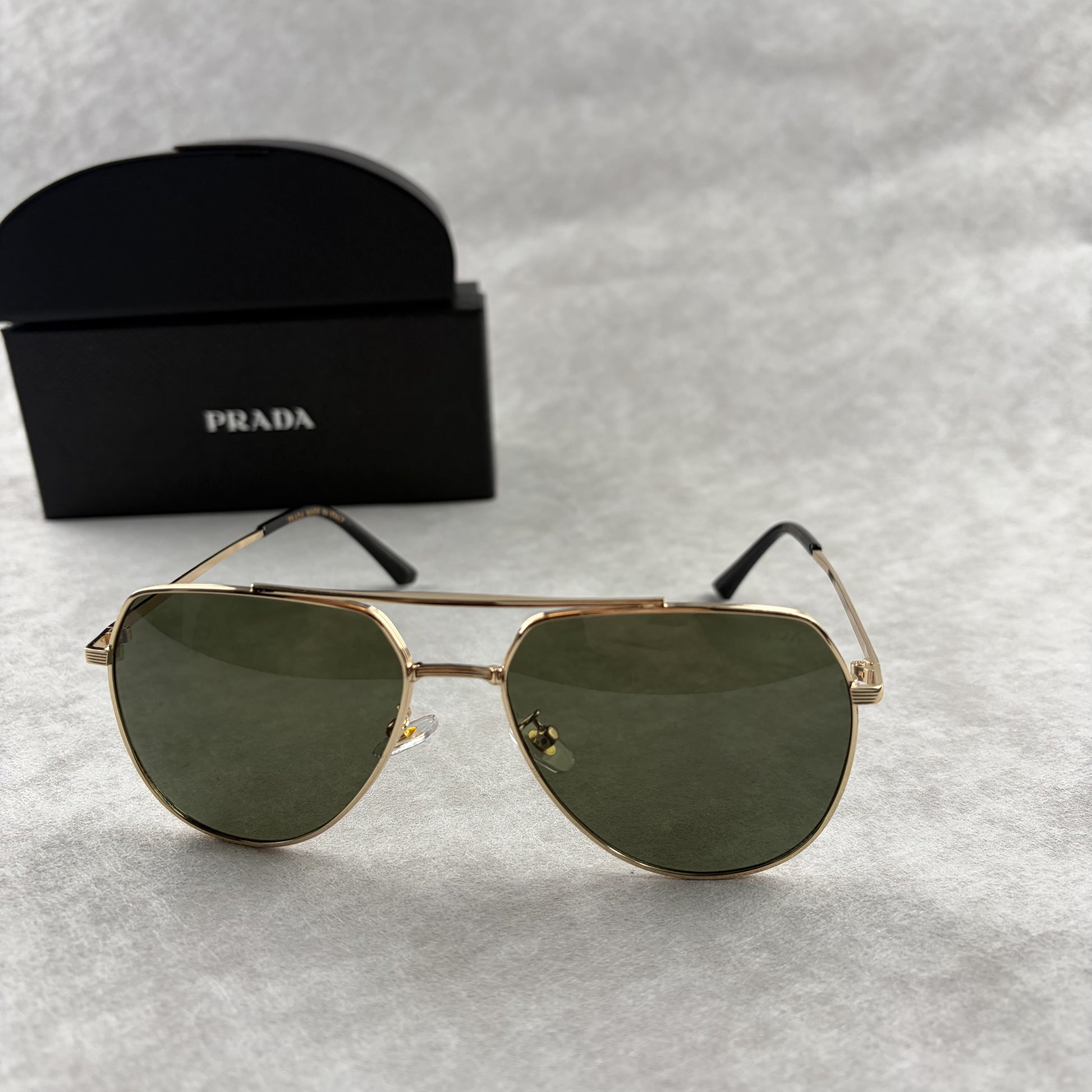 Classic gold-tone metal aviator sunglasses with tinted lenses, resting next to a protective case.