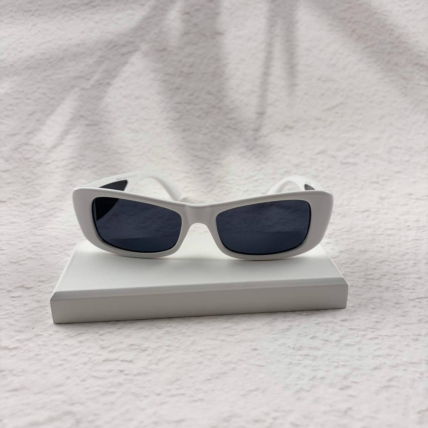 A pair of modern rectangular sunglasses with a bright white frame and dark tinted lenses.