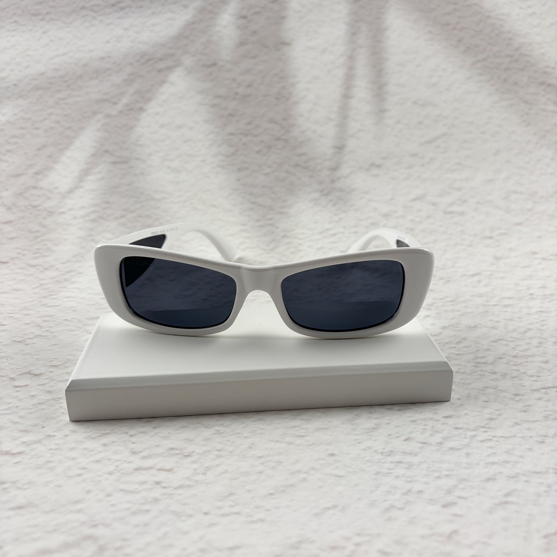 A pair of modern rectangular sunglasses with a bright white frame and dark tinted lenses.
