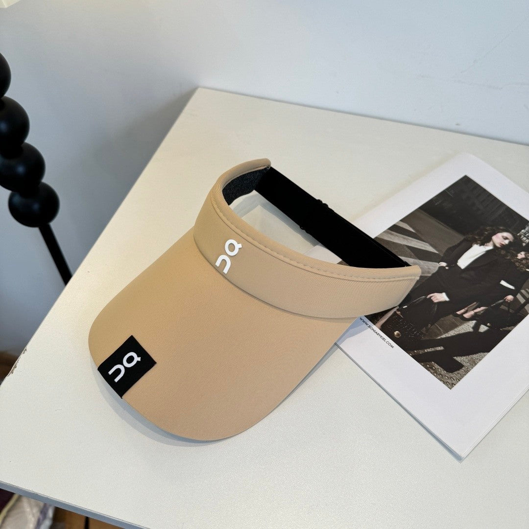 A beige lightweight sport visor with adjustable elastic band, featuring a minimalist logo design.