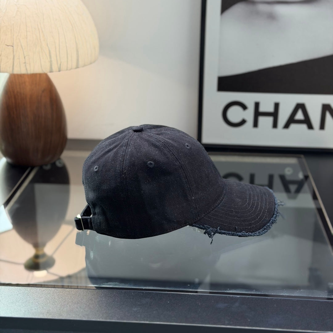 A black cotton baseball cap with a distressed brim and a small metallic circular side detail.