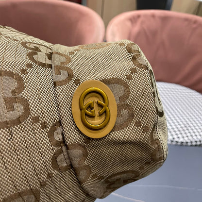 A beige canvas bucket hat with an all-over brown monogram pattern and a decorative gold-toned emblem