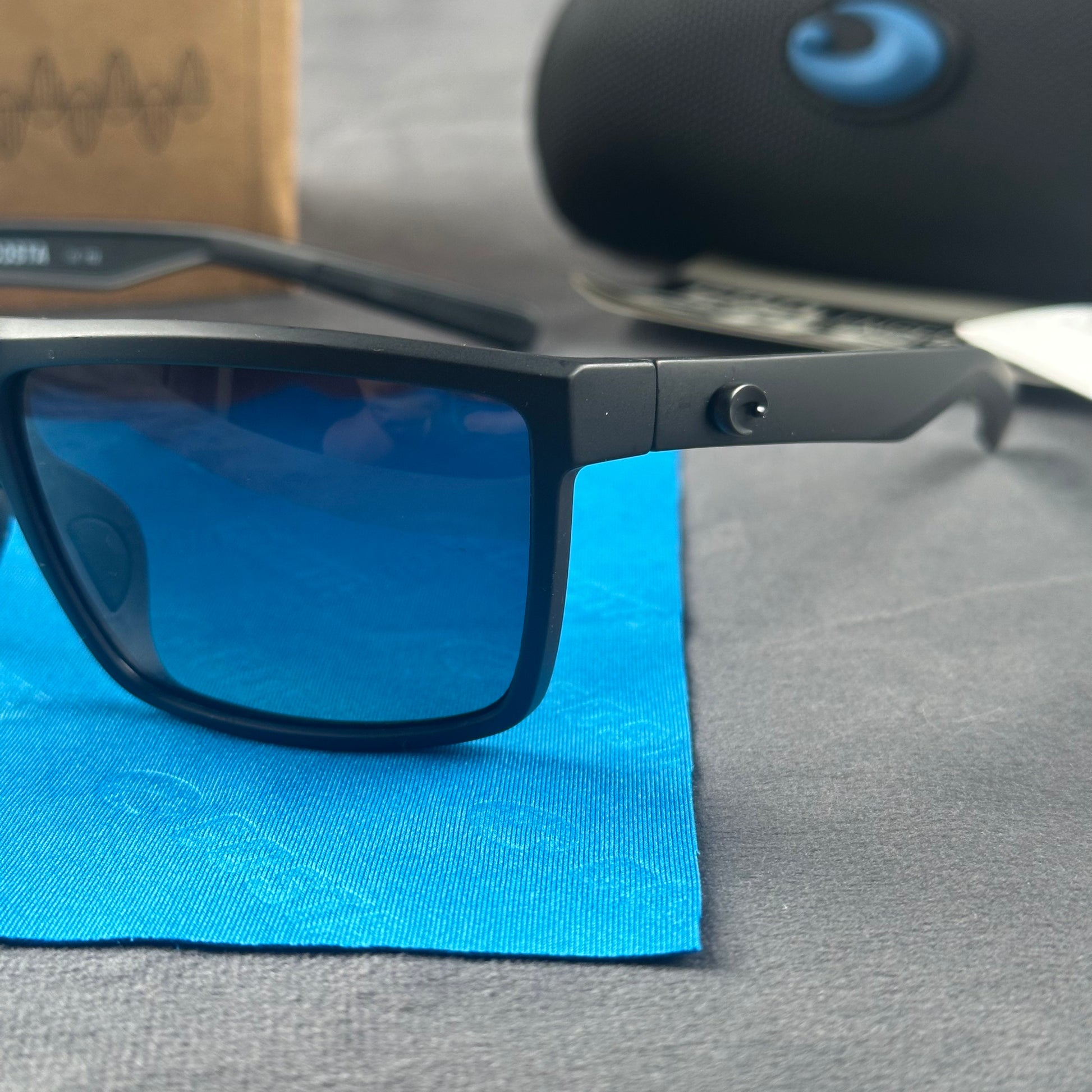 Matte black sport sunglasses with polarized blue-tinted lenses, hard case, and cleaning cloth.