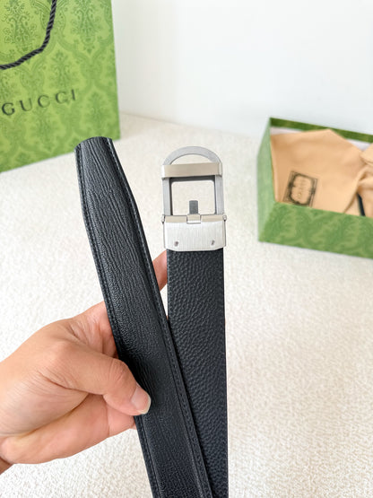 Black textured genuine leather belt with a modern metallic geometric buckle on a white surface.