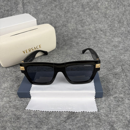 Black square-frame sunglasses with gold-tone metal temple accents, resting on a white cleaning cloth