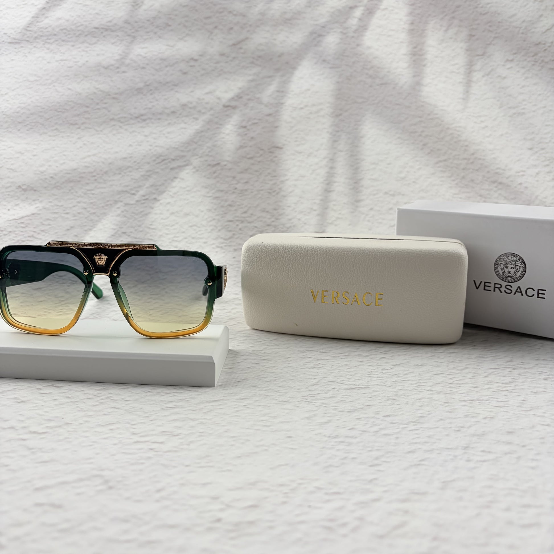 Oversized geometric sunglasses with green-to-yellow gradient lenses and gold metallic frame details.