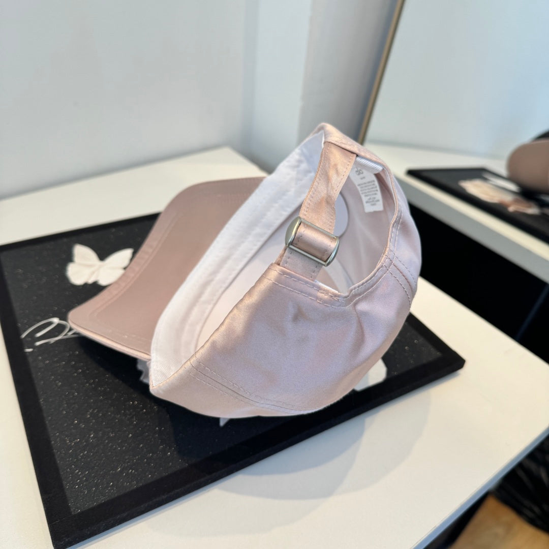 Dusty pink satin baseball cap with a curved brim, featuring a minimalist adjustable back strap.
