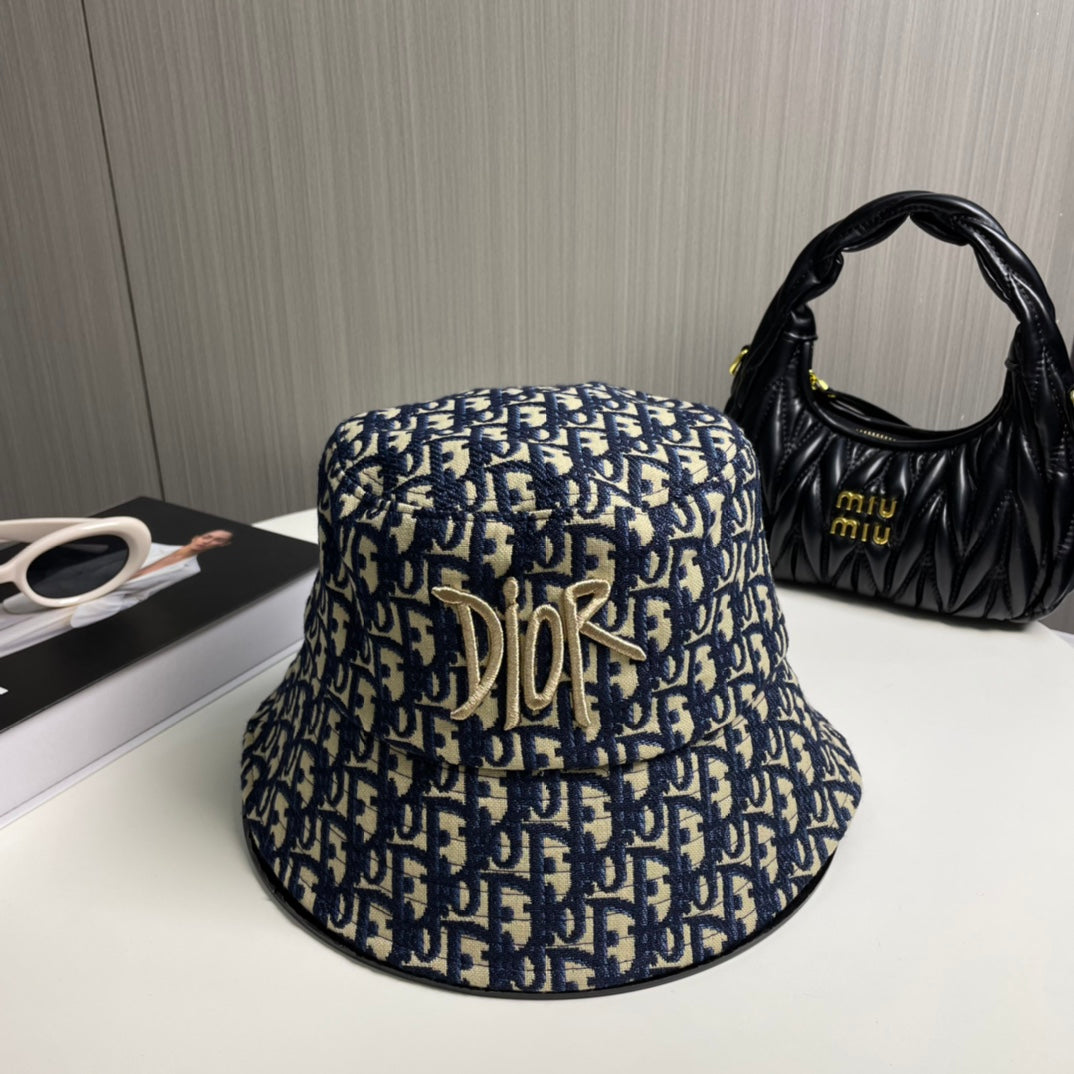 Close-up of a premium navy and beige monogram patterned bucket hat with central gold embroidery.