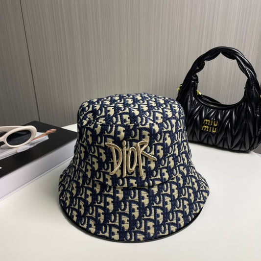 Close-up of a premium navy and beige monogram patterned bucket hat with central gold embroidery.