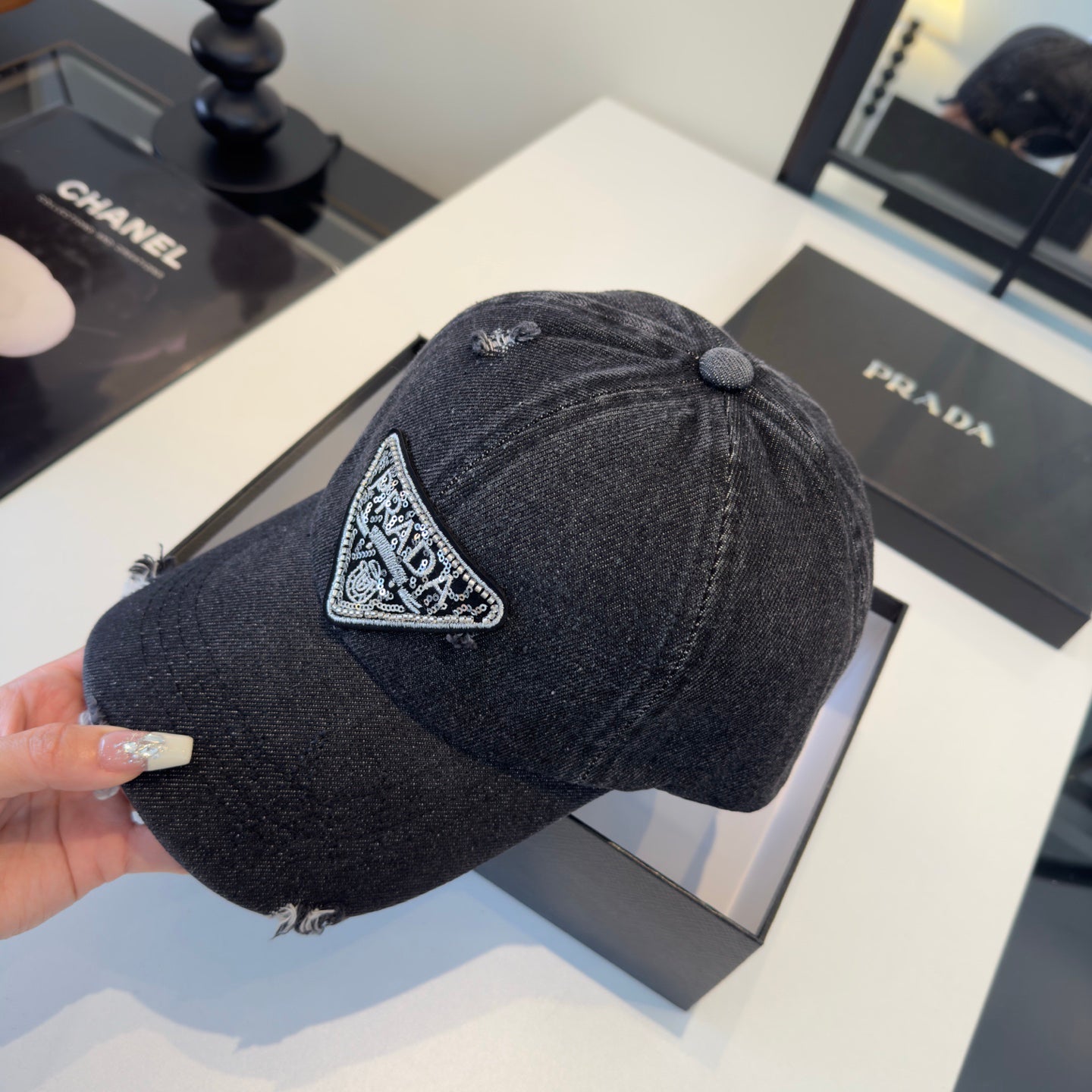 A black distressed denim baseball cap with a sparkling triangular patch on the front center.