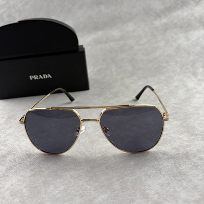 A pair of gold metal aviator sunglasses with dark lenses resting on a light grey textured background