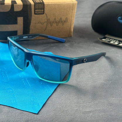 Blue and teal gradient frame sport sunglasses with polarized lenses resting on a blue cloth.