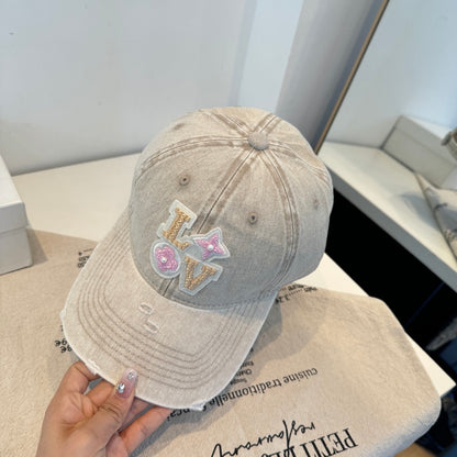 Distressed beige baseball cap with intricate floral letter embroidery and pearl details.