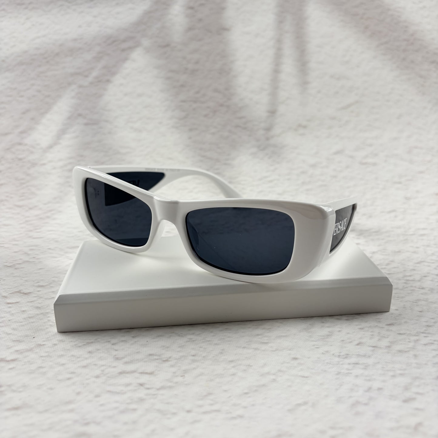 A pair of modern rectangular sunglasses with a bright white frame and dark tinted lenses.