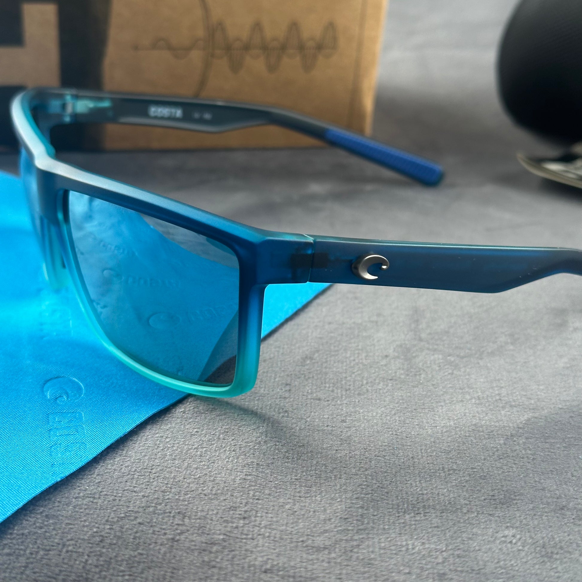 Blue and teal gradient frame sport sunglasses with polarized lenses resting on a blue cloth.