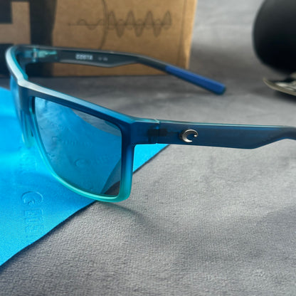 Blue and teal gradient frame sport sunglasses with polarized lenses resting on a blue cloth.