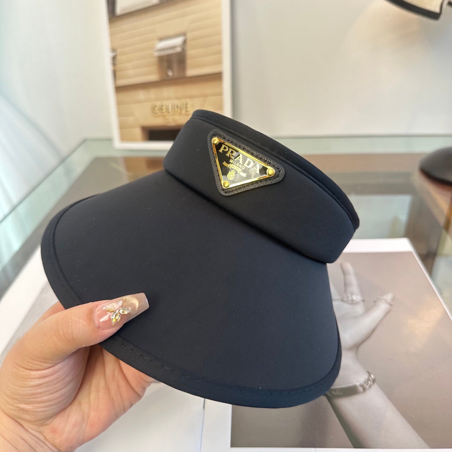 A sleek black wide-brim sun visor featuring a gold triangular emblem, designed for sun protection.