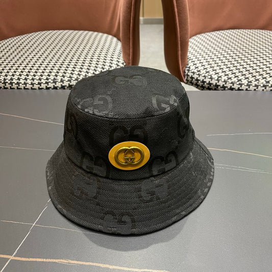 A black textured bucket hat with a circular gold emblem, featuring a monogrammed fabric design.