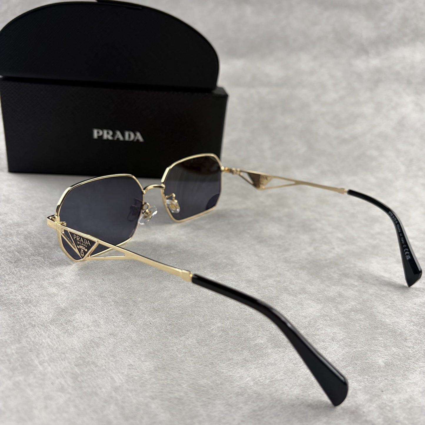 Geometric metal-frame sunglasses in gold tone with dark smoke lenses and signature triangular temple