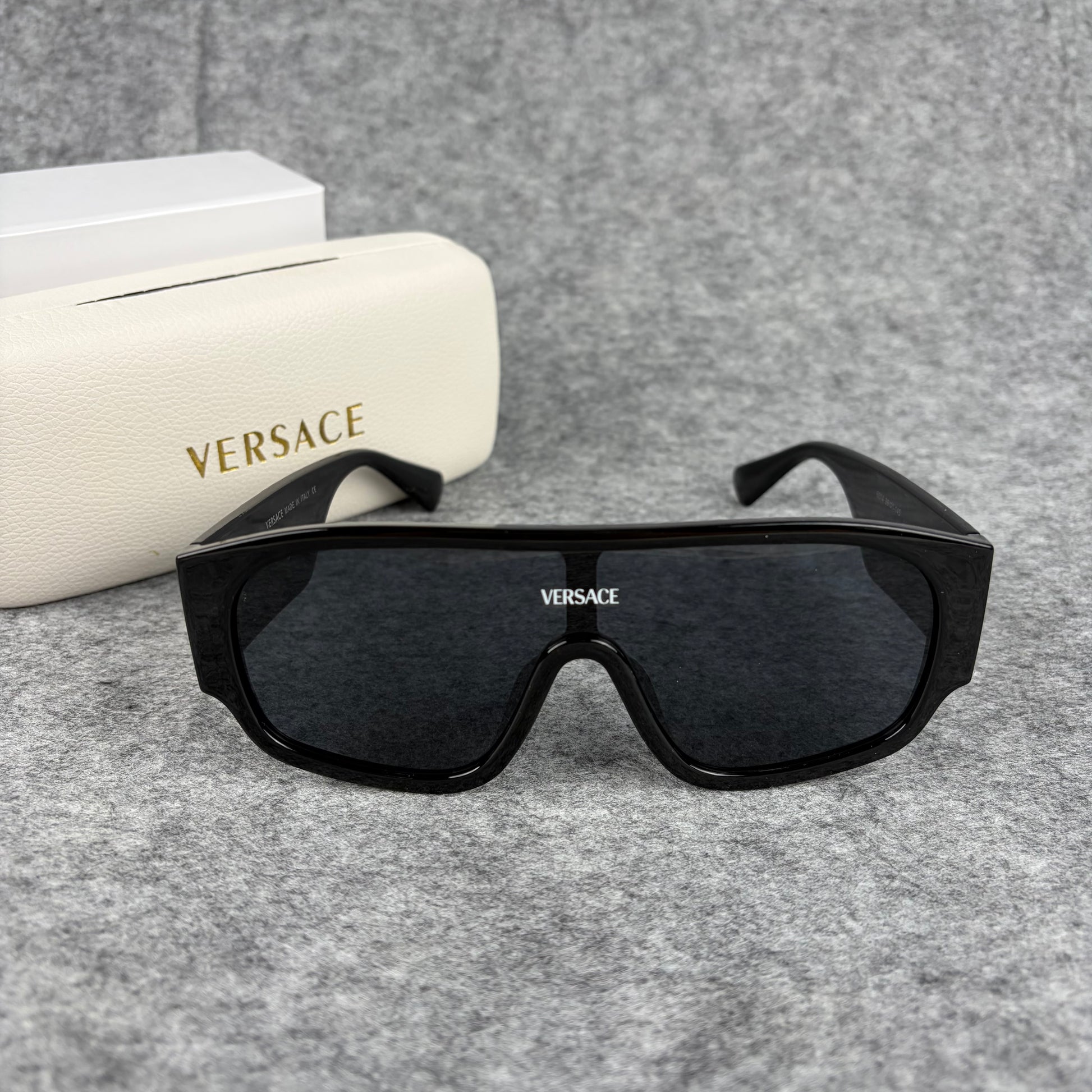 Oversized black shield sunglasses with a clean, modern aesthetic and protective hard storage case.