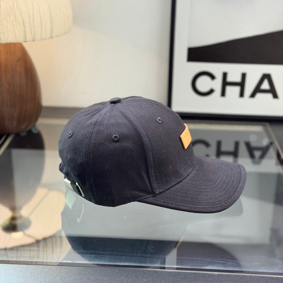 A structured black cotton baseball cap with a rectangular tan faux-leather patch on the front.