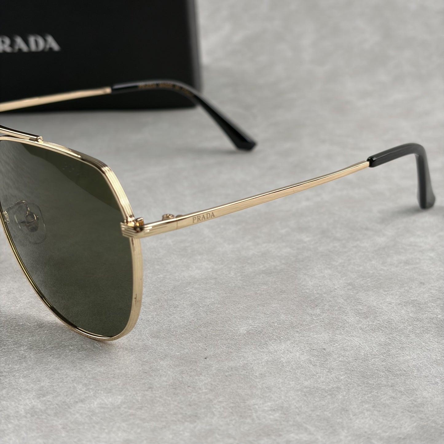 Classic gold-tone metal aviator sunglasses with tinted lenses, resting next to a protective case.