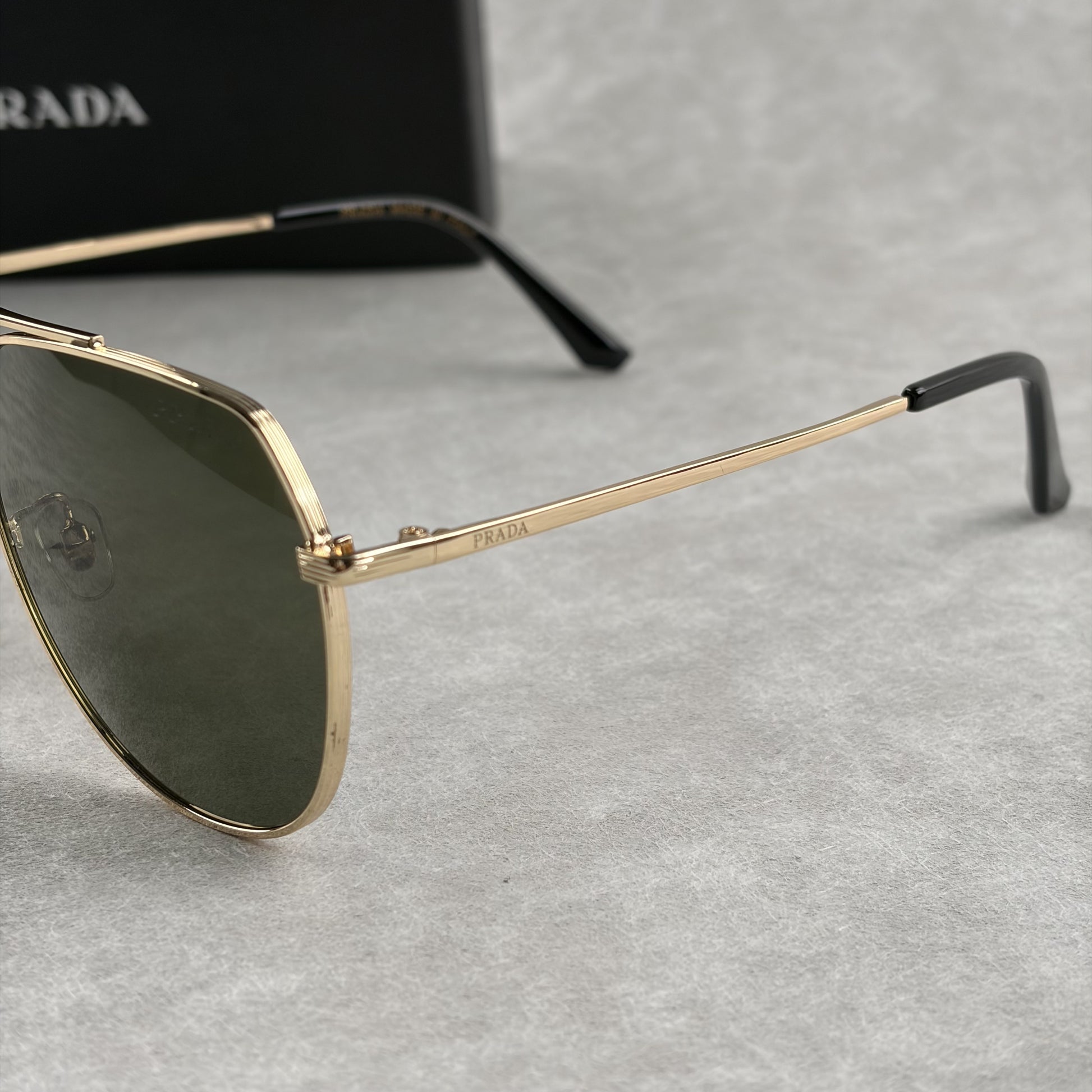Classic gold-tone metal aviator sunglasses with tinted lenses, resting next to a protective case.
