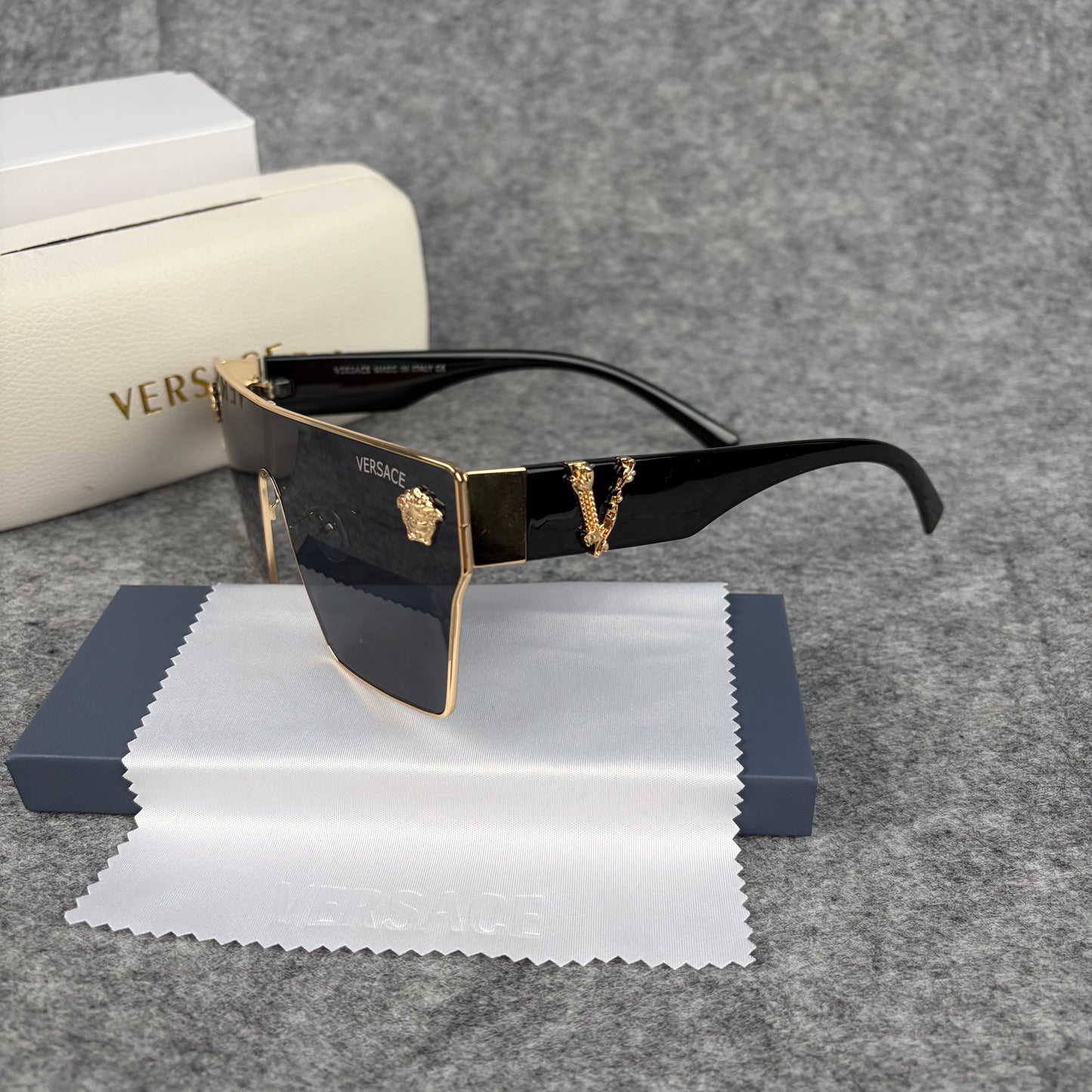 Oversized flat-top shield sunglasses with black lenses and decorative gold-tone metal side accents.