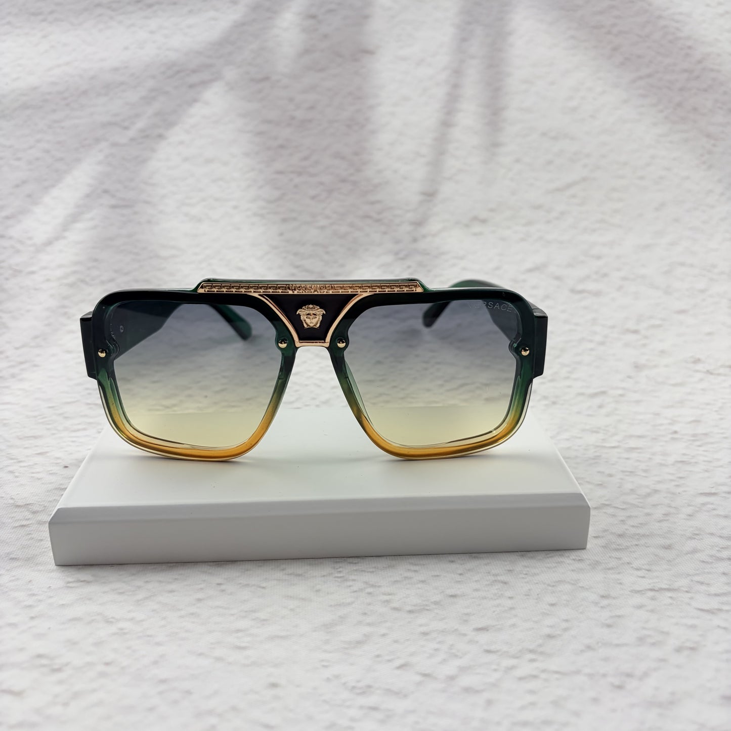 Oversized geometric sunglasses with green-to-yellow gradient lenses and gold metallic frame details.