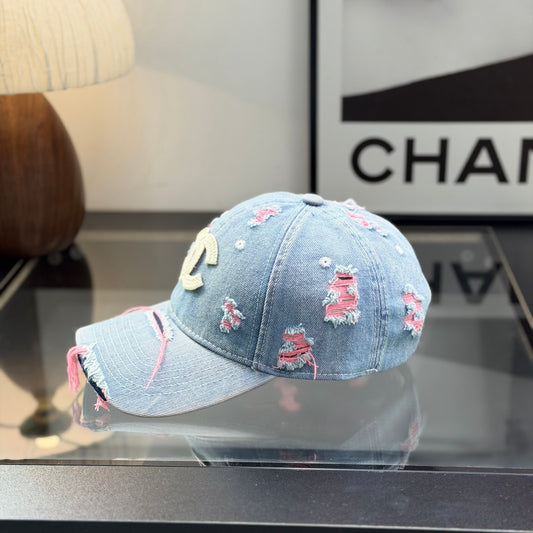 Distressed light wash denim baseball cap with frayed pink stitching and embroidery on the front.