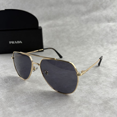 A pair of gold metal aviator sunglasses with dark lenses resting on a light grey textured background