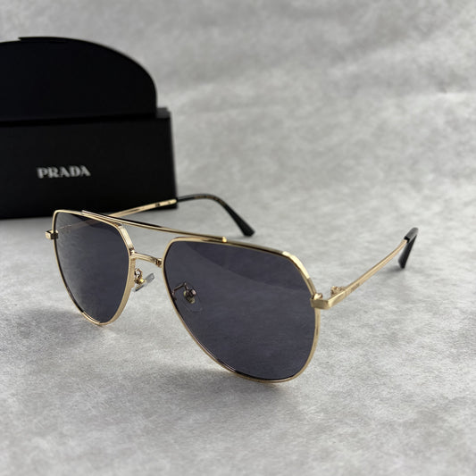A pair of gold metal aviator sunglasses with dark lenses resting on a light grey textured background