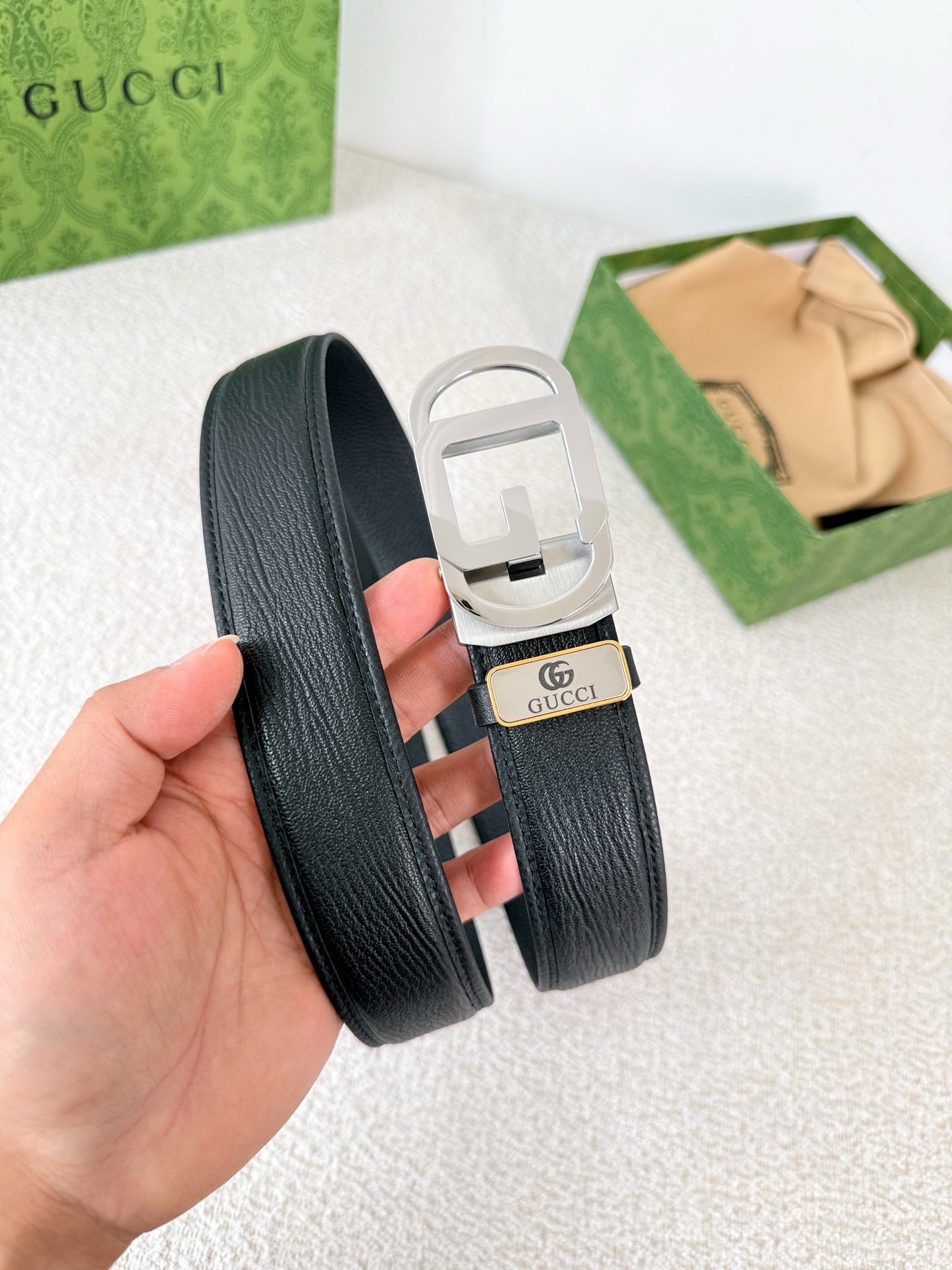 Premium black leather belt with a modern silver automatic steel buckle and detailed grain texture.