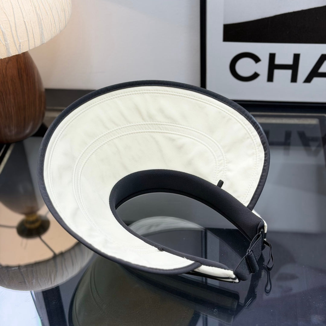 A stylish off-white open-top sports visor with black trim and embroidered text detailing.