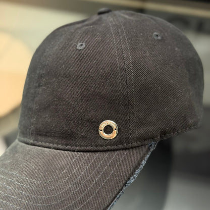 A black cotton baseball cap with a distressed brim and a small metallic circular side detail.