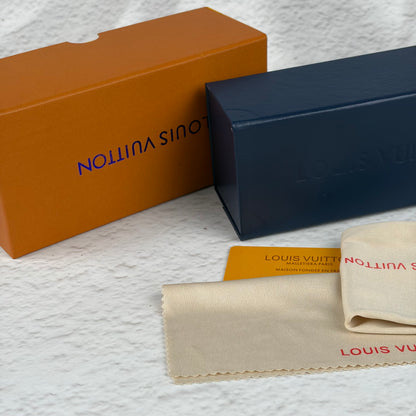 Rimless sunglasses with gold metal arms and dark gradient lenses resting on a white display block.