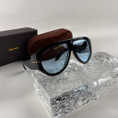Black acetate oversized aviator sunglasses with blue tinted lenses resting on a clear ice-like block
