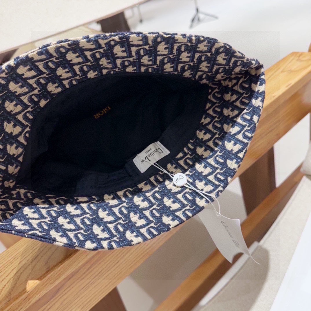 Close-up of a blue and beige monogram patterned cotton bucket hat with a wide brim and fabric band.