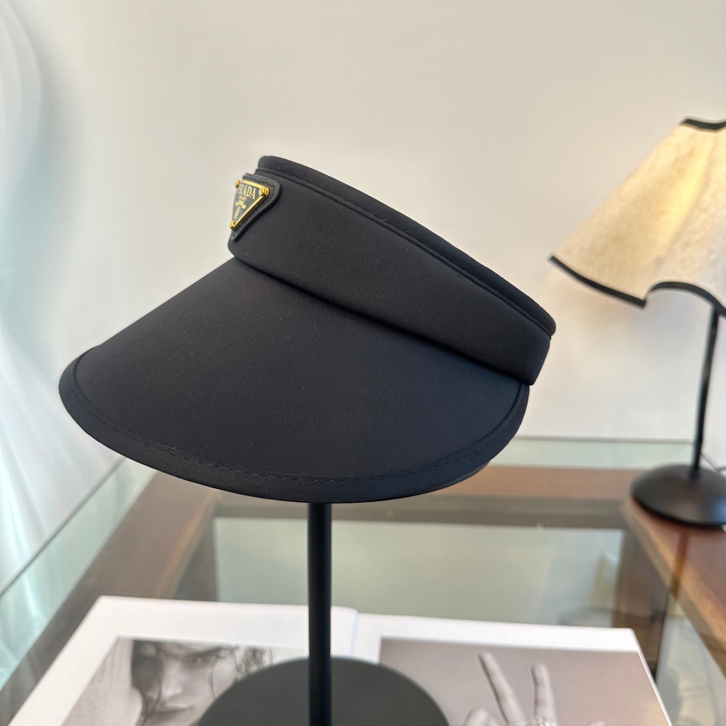 A sleek black wide-brim sun visor featuring a gold triangular emblem, designed for sun protection.