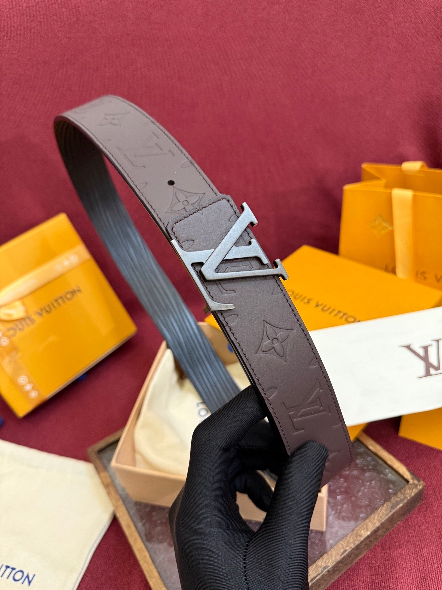 Close-up of a brown embossed leather belt featuring a matte metal buckle and patterned surface.